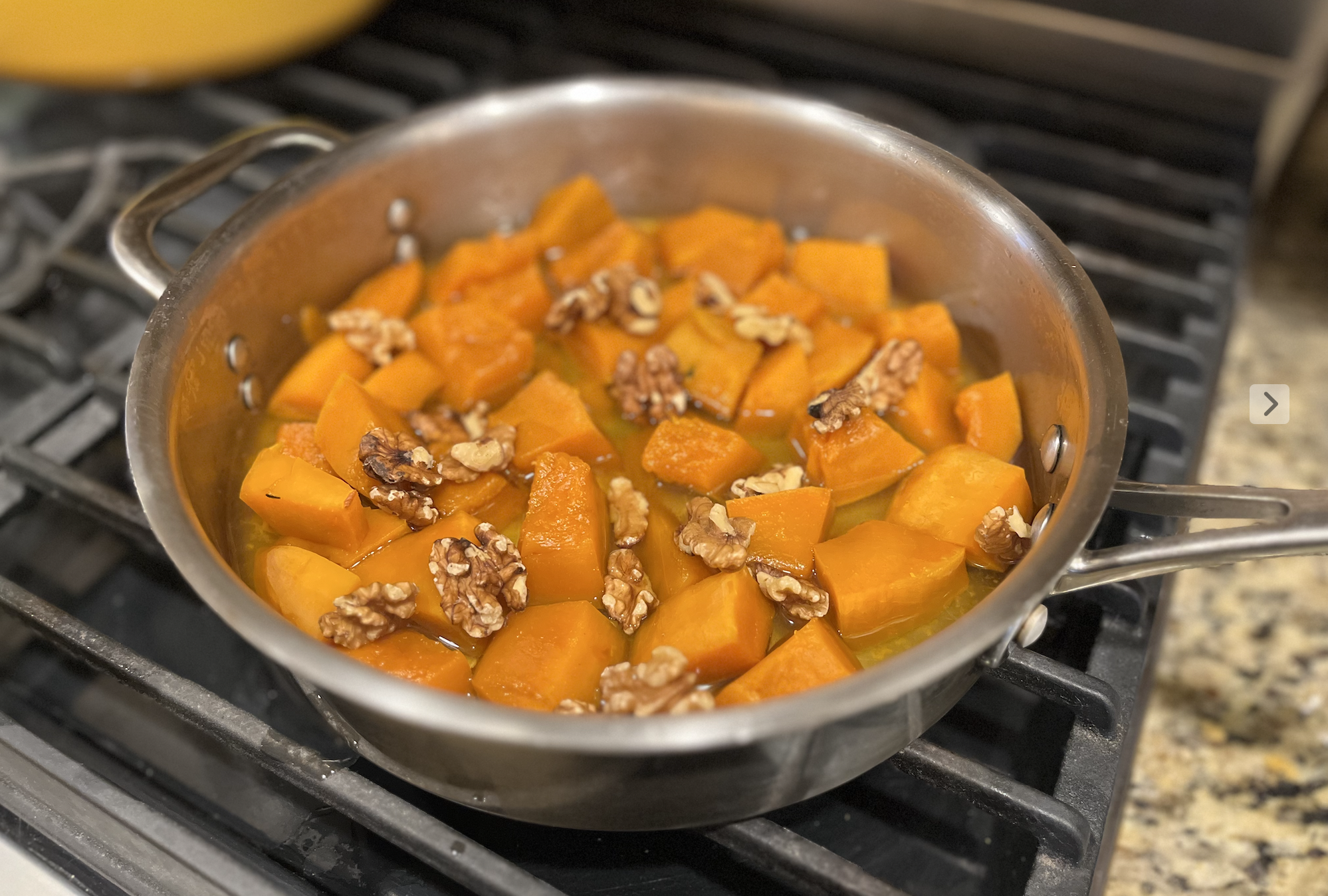 cubed pumpkin poached in syrup with walnuts on a stove