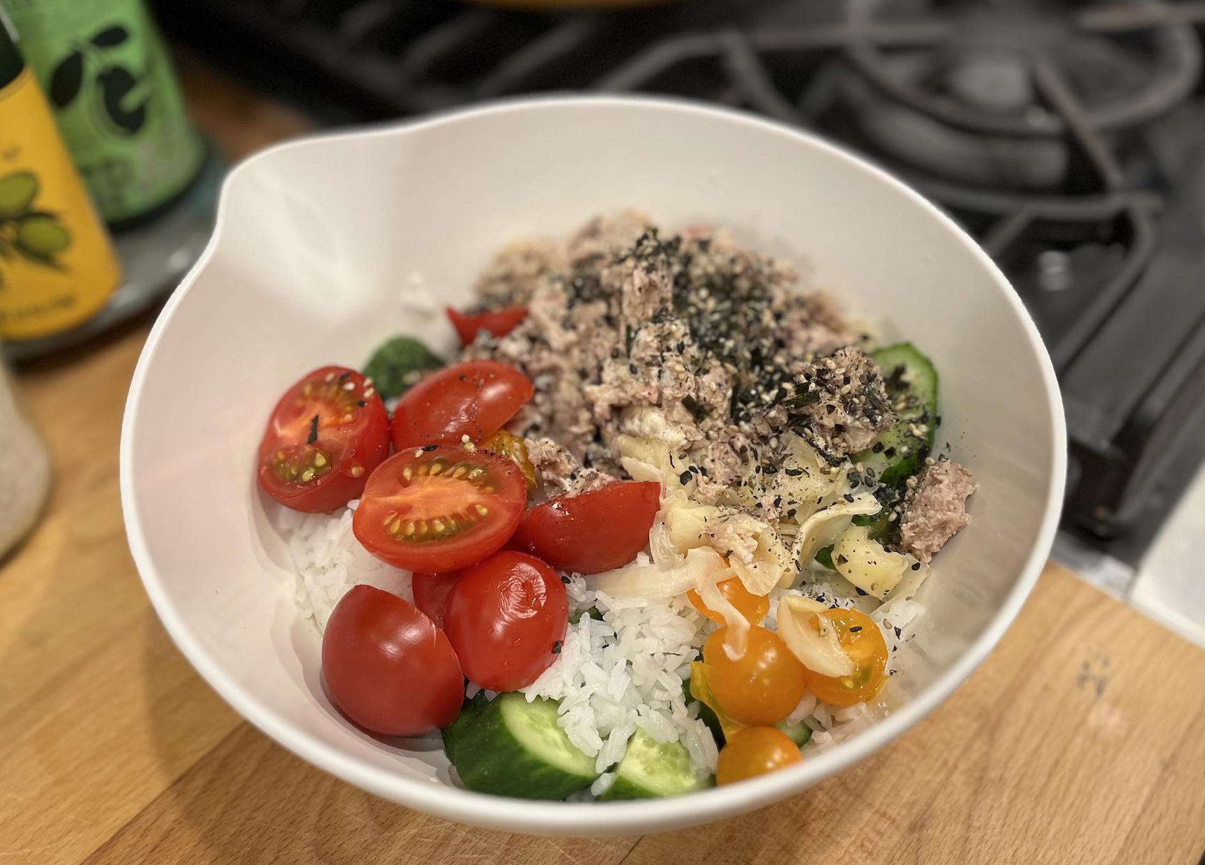 a bowl of rice and sardines and tomatoes and cucumbers and ginger