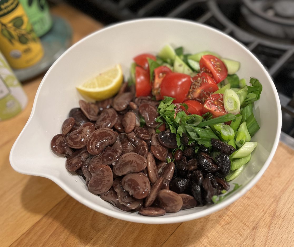 a bowl of christmas lima beans and tomato celery with a lemon wedge