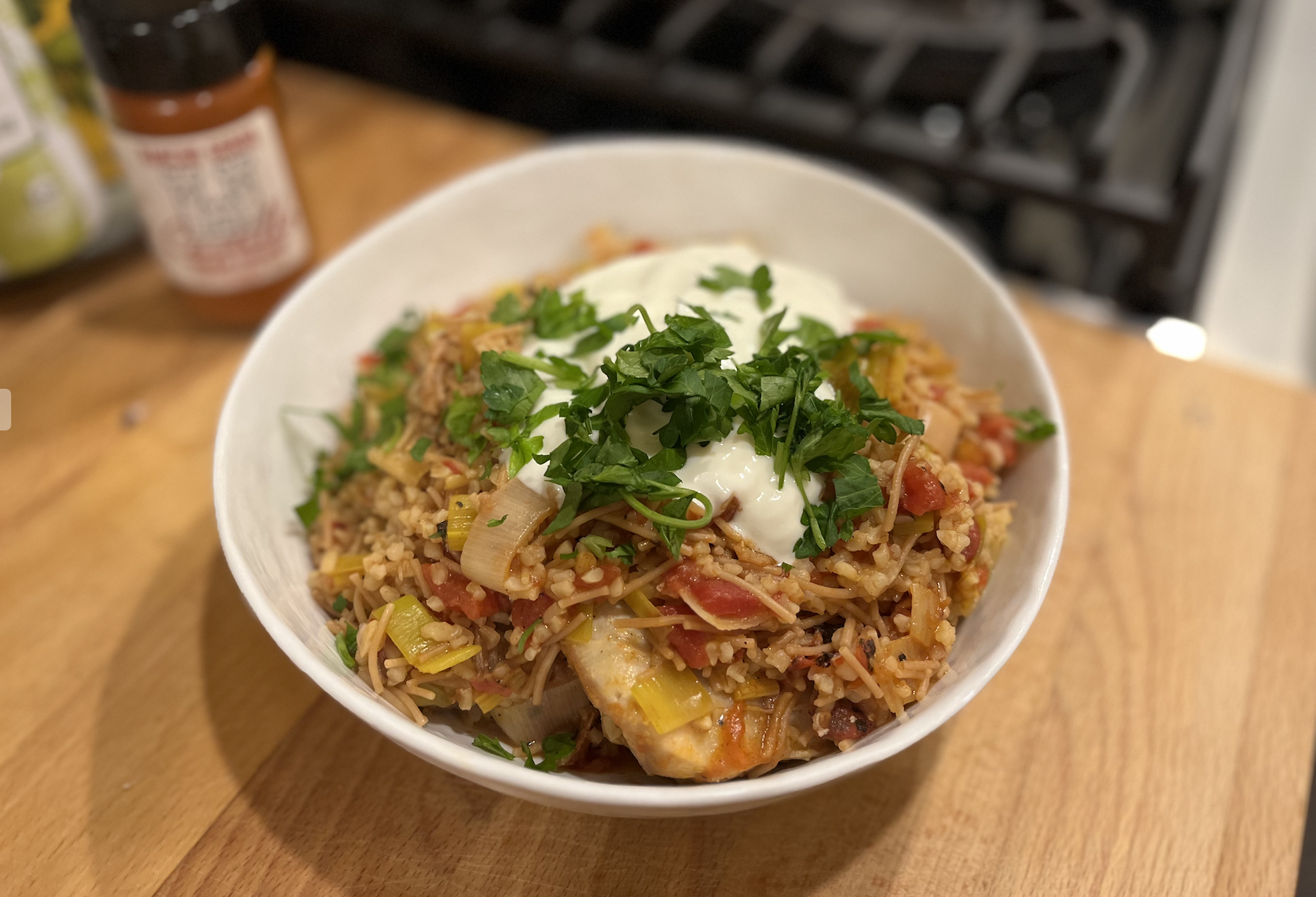 a bowl full of chicken and bulgur with yogurt and parsley